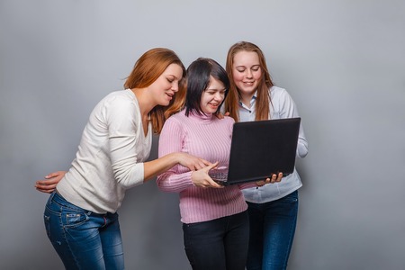 Three girls girlfriends, looking laptop on a gray  backgroundの写真素材