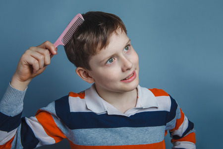 European-looking boy of ten years combing her hair の写真素材