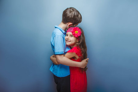 teen  girl hugging a  teenage  boy on  gray  backgroundの写真素材