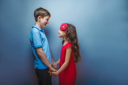 teen girl holding hands teenage boy on gray backgroundの写真素材