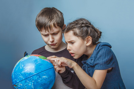 Teenage boy with a girl looking at a globe showing thumbs up onの写真素材
