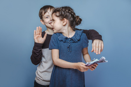 girl holding money bills in the hands of a boy trying to take awの写真素材