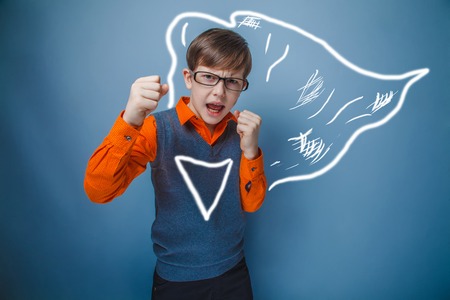 European-looking boy of ten years in glasses, anger, opened his mouth, his fists on a gray backgroundの写真素材
