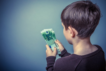 teenager boy Brown European appearance counts the money on a gray background, bill, bill retro photo effectの写真素材