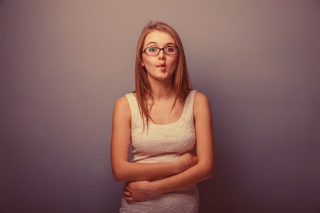 European appearance blonde girl pursed his lips forward on a gray background, mischief retroの写真素材