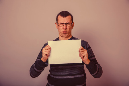 European-looking man of 30 years holding a blank sheet of discontent retroの写真素材