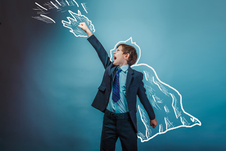 superhero boy raised his hands superpower businessman flying behind a cloak photo studio teenagerの写真素材