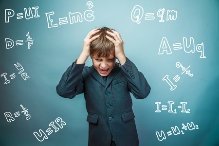 Teen boy scientist fails holding his head formula physics science studio background experiencing problemsの写真素材