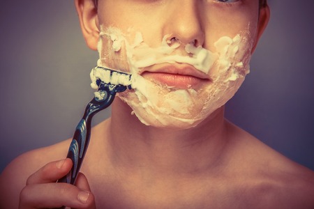 the boy of the European appearance decade person shaves, shaving  foam on a  gray  background retroの写真素材