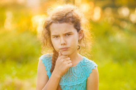 Teenage girl is thinking on a green background on the nature of the outside hand under his chin...