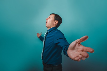 a man of European appearance thirty years spread his arms singing on a gray backgroundの写真素材