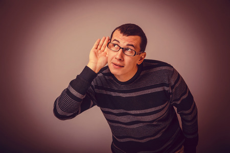 male of European appearance brunet put his hand to his ear, eavesdropping cross process retroの写真素材