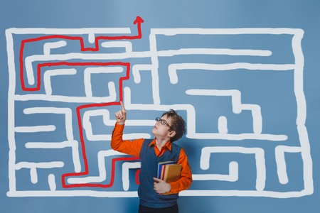 a boy of twelve European appearance in a suit holding a blank sheet on a  gray  backgroundの写真素材