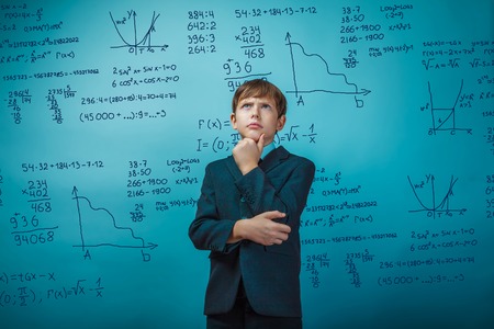 a boy of twelve European appearance in a suit holding a blank sheet on a  gray  backgroundの写真素材