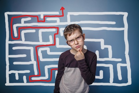 a boy of twelve European appearance in a suit holding a blank sheet on a  gray  backgroundの写真素材