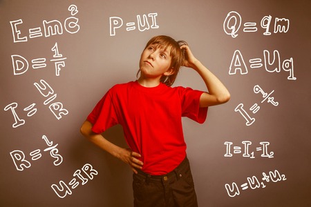 European-looking boy of ten years thinking, scratching his head on a gray background retroの写真素材