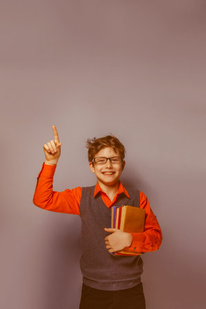 European-looking  boy of  ten years  in glasses  thumbs up, the idea of the book on a gray background retroの写真素材
