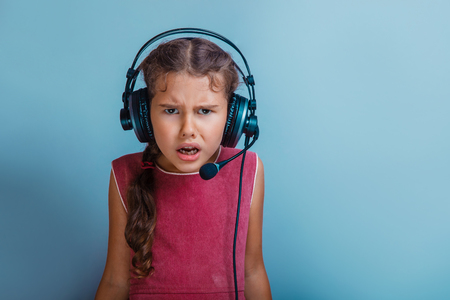 Girl European appearance decade listening to music with headphones open mouth on a blue backgroundの写真素材