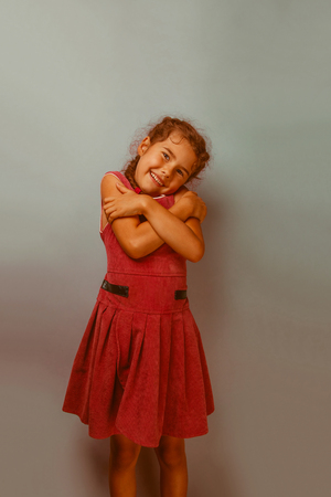 Girl European appearance decade hugging herself on a blue background retroの写真素材
