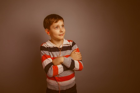 r boy of about ten European appearance Brown listens vacuum headphones orange on gray background, sm retroの写真素材