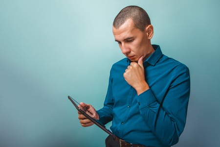 a man of European appearance thirty years looking into the plate thinking on a gray backgroundの写真素材