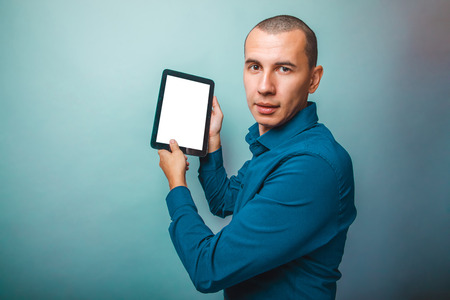 a man of European appearance thirty years shows a plate on a gray backgroundの写真素材