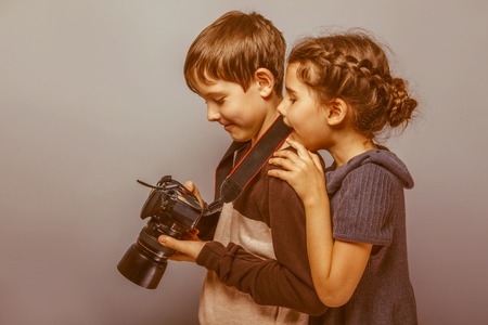 Teenage boy with a girl watching pictures on the  camera  on a gray  background retroの写真素材