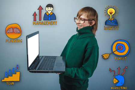 teen boy with glasses and a green sweater laughing and holding a laptop hands of a collection of business icons management team goal sketchの写真素材