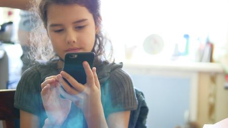 Girl in kitchen playing smartphone online games breakfast social mediaの写真素材