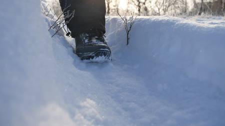 man walking in snow in winter boots, winter nature beautiful landscapeの写真素材