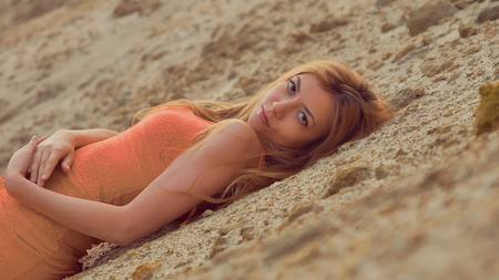 blonde girl lie on the sand and looking at the camera sexyの写真素材