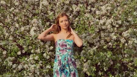 girl in a dress smiling near blossoming treeの写真素材
