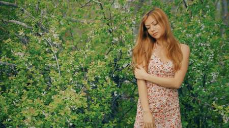 young girl posing against a background of flowering gardenの写真素材