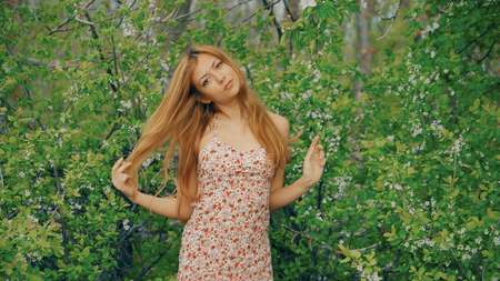 young girl posing against a background of flowering gardenの写真素材