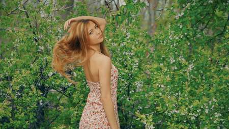 young girl posing against a background of flowering gardenの写真素材