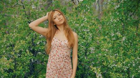 young girl posing against a background of flowering gardenの写真素材