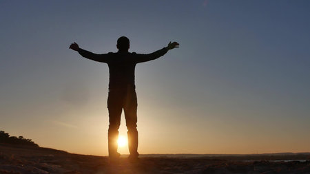 freedom. Man stands on a cliff sunset silhouette hand lifestyle in the sides