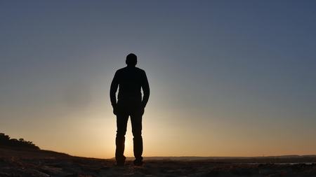 freedom. Man stands on a cliff sunset silhouette hand in lifestyle the sidesの写真素材
