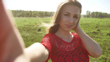 Selfie. The girl makes selfie, takes pictures of herself in nature. Girl hair breeze lifestyleの写真素材