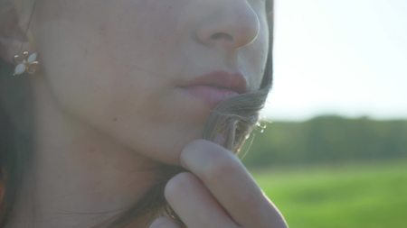 Girl lips. Girl is standing on the nature hair touch lips, strong lifestyle windの写真素材
