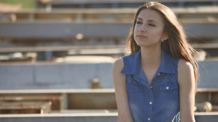 The girl is sitting on the bridge. Sexy beautiful lifestyle girl sits on the bridge outdoorの写真素材