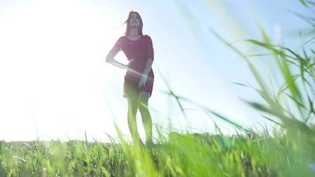 Girl wind nature. The girl is standing in the field of green grass. Woman freedom lifestyleの写真素材