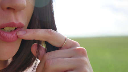 The girl touches her lips and her hair flutters in the wind. Sexy girl nature lifestyleの写真素材