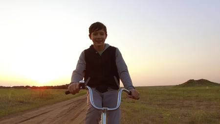 Boy teenager riding bicycle. Boy teenager riding bicycle goes to nature along the path steadicam shot motion videoの写真素材