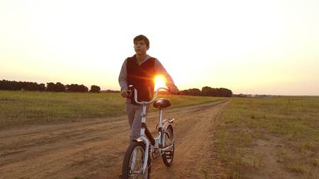 Boy teenager riding bicycle. the Boy teenager riding bicycle goes to nature along path steadicam shot motion videoの写真素材