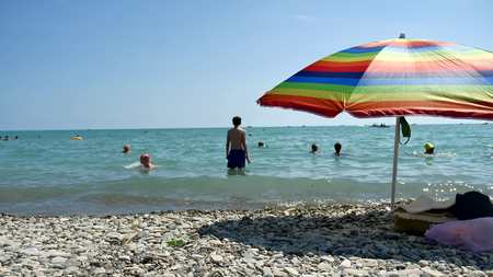 People bathing in the sun, swimming and playing games on the beach. Tourists on the beach from the pebbles sea oceanの写真素材