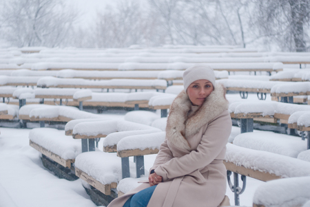 Winter portrain of a woman in white coat during snowfall in the parkの写真素材