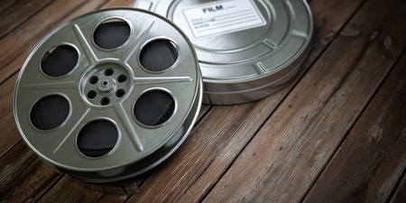 Vintage film reel with filmstrip on woodの写真素材