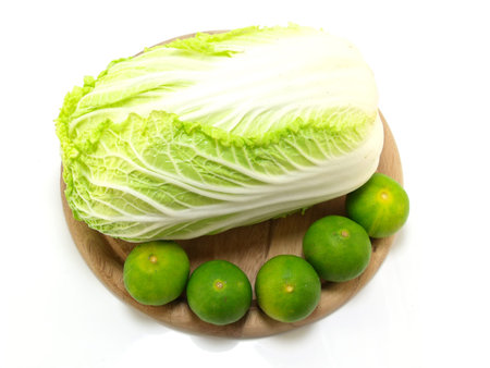 fresh green cabbage and lime on wooden chopping board over white background