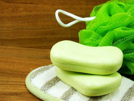 green soap and plastic bath puff on wooden backgroundの写真素材